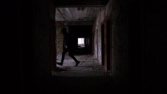 young man running in long corridor and entrances of an old abandoned building. Slow motion video. The concept of loneliness, labyrinths of fate, search for answers to questions