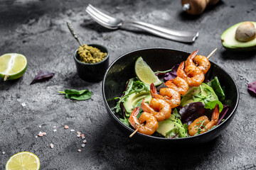 Vegetarian vegetable low carb lunch bowl with avocado, fresh salad, grilled shrimps and pesto sauce. Healthy diet seafood concept. Top view