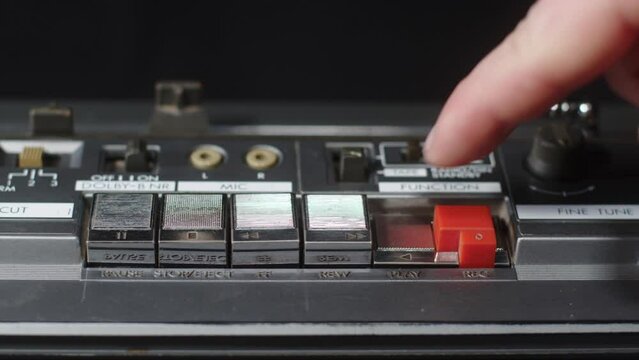 Finger presses the play button on an old vintage cassette recorder - close-up