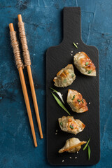 Fried dumplings with pork and greens on a black graphite board