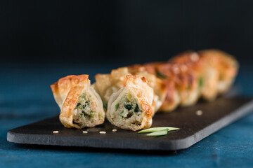 Fried dumplings with pork and greens on a black graphite board