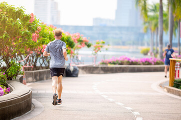 Man is jogging in a park in the city. Active healthy runner jogging outdoor. Running in city park....