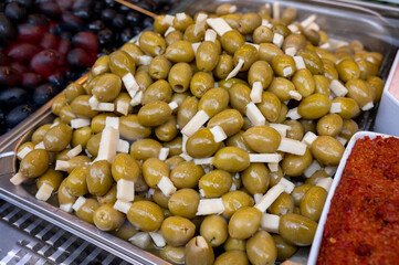 Green olives with cheese close up on market, food background