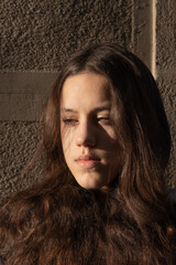 Close up portrait of young attractive girl with grey eyes and dark open hair. Girl with serious facial expressions looking away from the camera. 