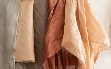 hand dyed clothes in warm natural tones hanging on a bright background - text space -
slow fashion concept  - 489508032