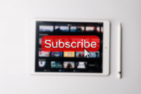 Subscription service. Online video red subscribe button. Internet service on laptop digital tablet blured technology background. Streaming video. Communication network.