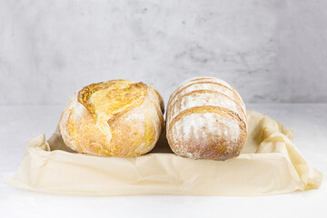 Fresh crusty bread on craft paper against gray background. Selective focus. Front view.