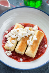 Pan fried georgian crepes with cottage cheese stuffing and strawberry sauce, close-up, vertical shot