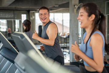 Fototapeta na wymiar Group of Healthy Asian athletic man and woman in sportswear jogging workout exercise on treadmill together at fitness gym. Wellness male and female do sport training on running machine at sport club
