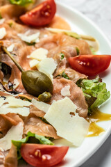 Salmon carpaccio with with capers, parmesan and cherry tomatoes. Delicious balanced food concept