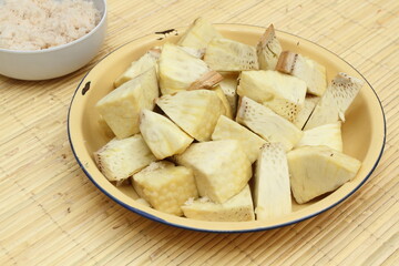 Steamed breadfruit (Artocarpus altilis) slices served on plate. A bowl of grated coconut on the background