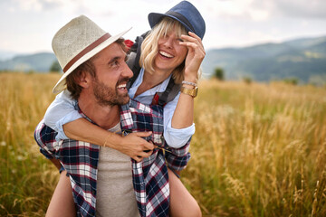 A young happy couple in love is playing while walking a meadow. Hiking, nature, relationship, together