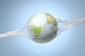 A globe wrapped in plastic wrap on a pastel blue background. Earth Day, World Environment Day....