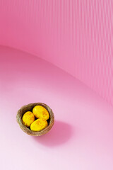 Easter eggs in a natural nest. Painted yellow-golden eggs on a pink background. Easter minimalistic concept. Copy space