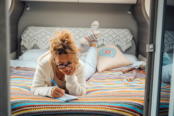 Adult woman laying and relaxin in camper van bedroom using paper notes to plan next destination....