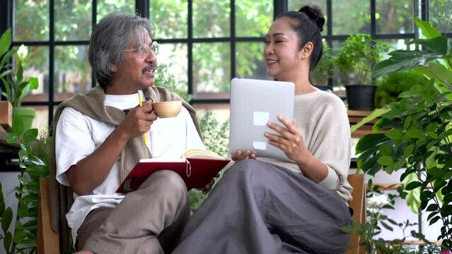 Senior couple asian family having good time using tablet computer together.Happy elderly husband and wife checking social media and reading news or shopping online while sitting at home	