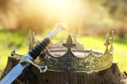 mysterious and magical photo of gold king crown and sword in the England woods. Medieval period concept.