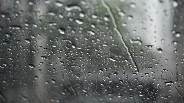 Raindrops run down on car windshield from inside view. Traffic jams during the heavy rain storm.