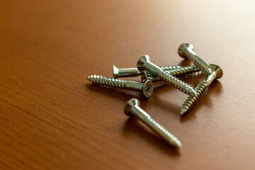 窓際の木の机に置かれた金属のネジ