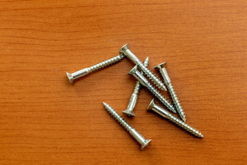 木の板の上に散らばる金属のネジ