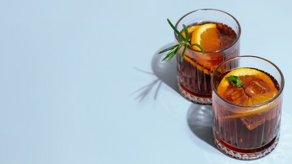Mezcal negroni cocktails. Two Alcoholic cocktails on blue background, copy space. 16x9 banner. 