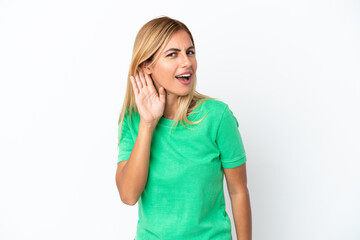 Blonde Uruguayan girl isolated on white background listening to something by putting hand on the ear