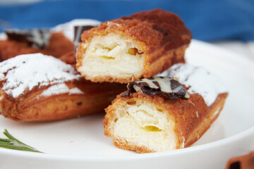 Beautiful delicious french eclairs set with original cream decor on white plate on wooden background, tasty colorful dessert profiteroles