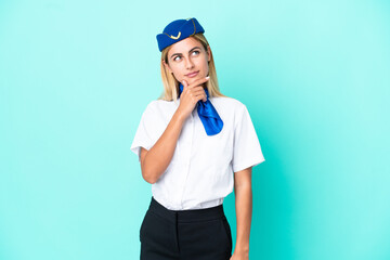 Airplane stewardess Uruguayan woman isolated on blue background having doubts and with confuse face expression