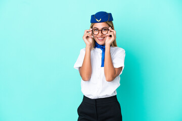 Airplane stewardess Uruguayan woman isolated on blue background with glasses and surprised