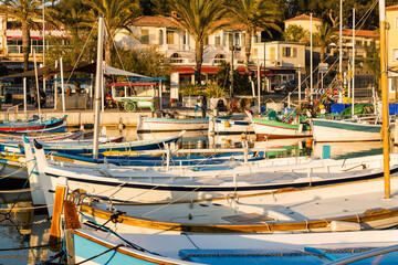 Fototapeta na wymiar Port de pêche côtière typique avec barques colorées alignées et palmiers sur le quai. Port de Sanary-sur-Mer, Méditerranée