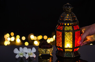 Lantern and dates fruit with white orchid flower on bokeh light background for the Muslim feast of the holy month of Ramadan Kareem.