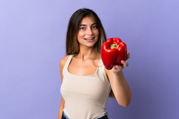 Young woman holding a pepper isolated on purple background with happy expression