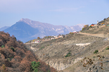 A village in the mountains. Living of people high in the mountains. Houses in a mountainous area. View of mountains, trees and houses.