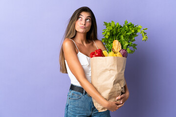 Young woman holding a grocery shopping bag and looking up