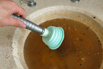 clogging in the kitchen sink-dirty dishwater accumulated in the sink-a person trying to open the kitchen sink with the sink pump,