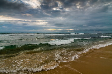 Summer landscape on the sandy shore of the Indian Ocean against the sky with clouds at sunset. Sri Lanka