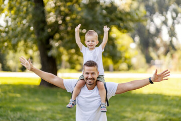 Happy family feeling freedom in nature, having piggyback ride and smiling at the camera.
