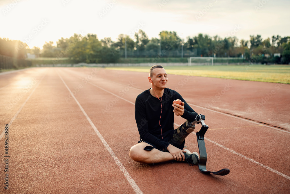 Canvas Prints A handicapped sportsman taking a break from sport, eating apple and relaxing with music.