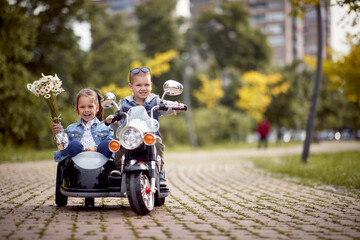 kids driving in motorcycle toy on battery in park