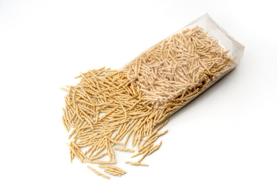 Trofie pasta, typical Italian pasta from Liguria, dried raw that come out of the transparent package on white background