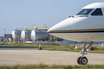 The nose of the aircraft against the background of fuel tanks at the airport.