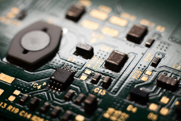 Macro photo of a green computer printed circuit board with selective focus on electronic components