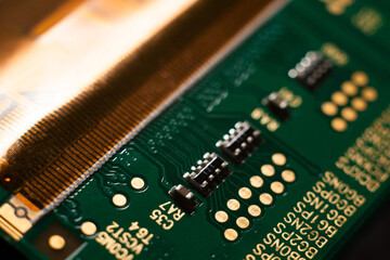 Macro photo of a green computer printed circuit board with selective focus on electronic components