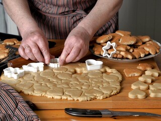 The process of making cookies in the kitchen from dough and molds.Hands of an elderly woman over the background.