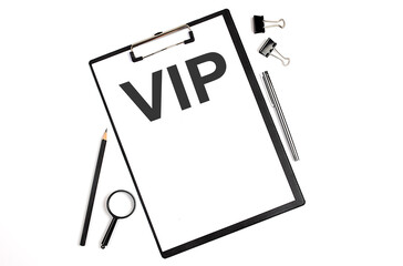 On a white background magnifier, a pen and a sheet of paper with the text VIP . Business concept