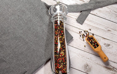 Culinary background, kitchen apron and pepper mill on the wooden background