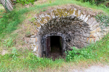 Cave à vin avec sa porte d'entrée ouverte et enterrée dans une colline sur le chemin de randonnée des caves de saint Julien dans le puy de dôme