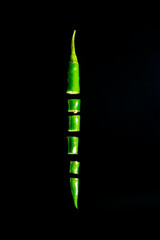 green chili pepper slices flying isolated on black  background