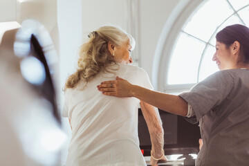 Female caregiver talking with elderly woman exercising on treadmill at retirement home
