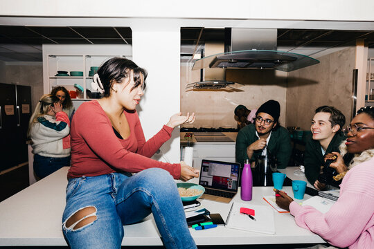 Young woman talking with multiracial roommates in college dorm